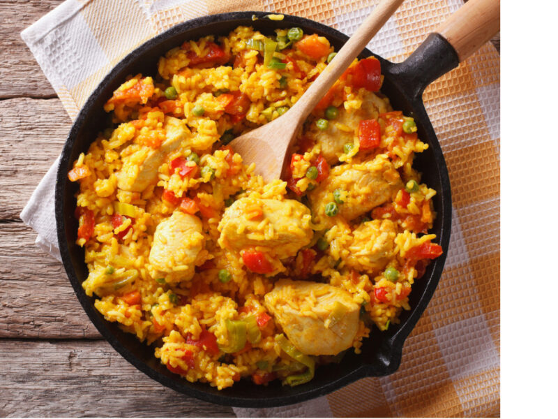 Cast iron pan with spoon in Spanish Chicken and Rice made with Old Havana Foods Sofrito