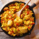 Cast iron pan with spoon in Spanish Chicken and Rice made with Old Havana Foods Sofrito